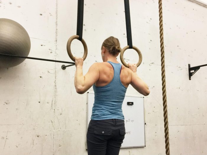 Woman using wooden rings for pull up