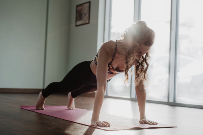 Woman performing a plank in front room