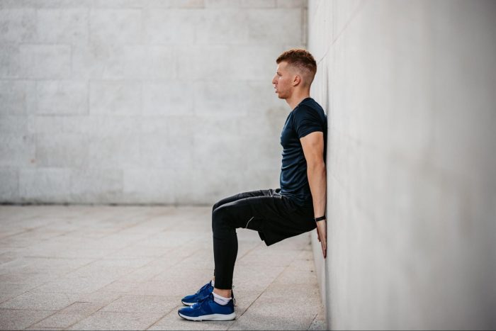 Man performing a wall sit outside