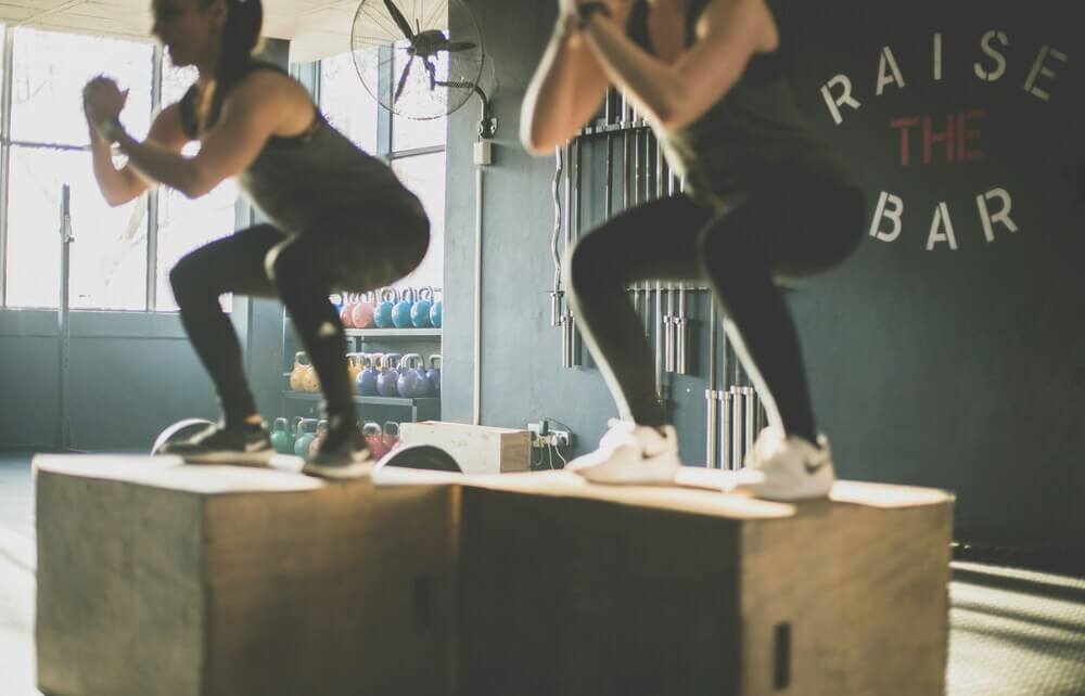Women functional training jumping onto boxes