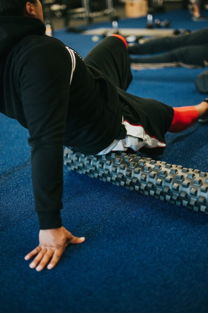 Man rolling out his hamstring in the stretching/ warm-up zone