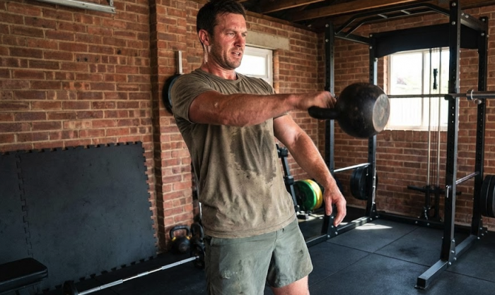 Man in a home gym swinging a kettlebell