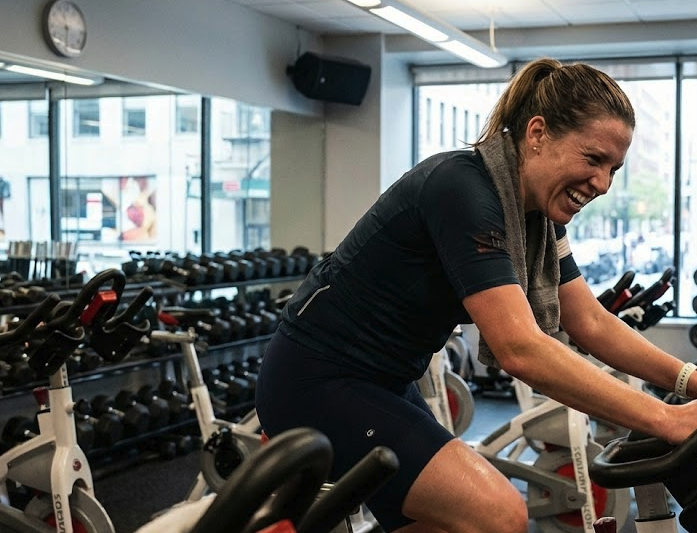Woman on a bike in a gym sweating