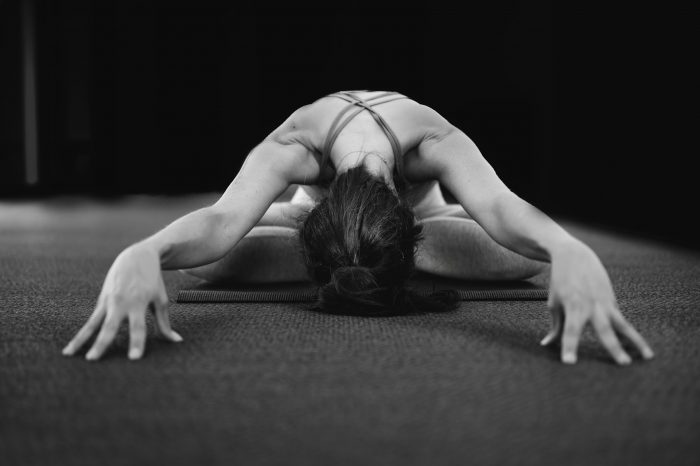 Woman with her legs crossed leaning forwards with her arms straight out stretching