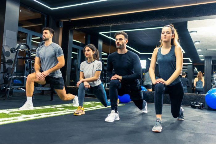 Group of four people, two male, two female squatting in a fitness class