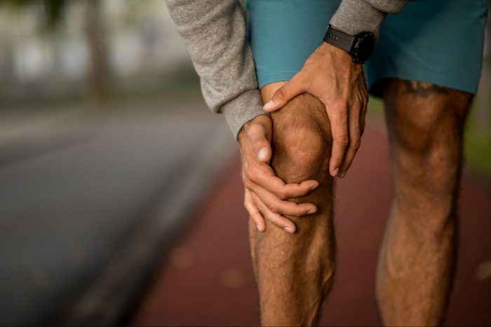 Runner holding their knee in pain