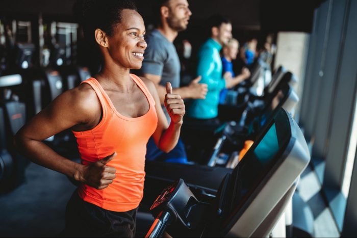 Woman in an orange top running on a treadmill