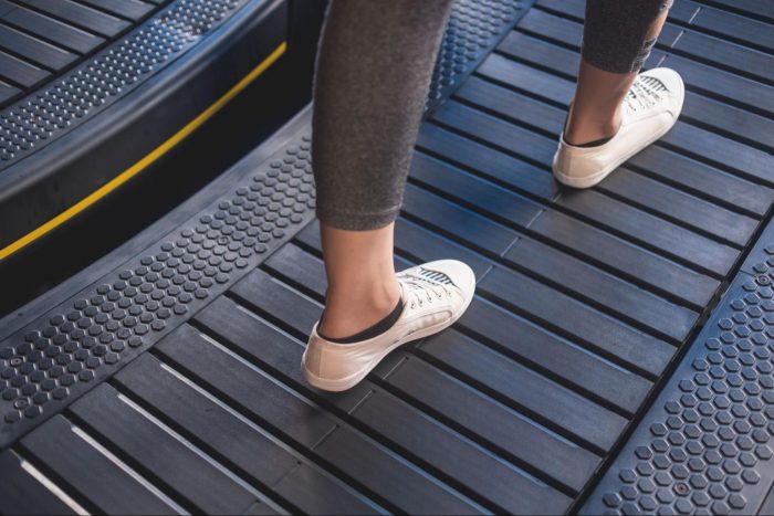 Someone in white shoes walking on a curved treadmill
