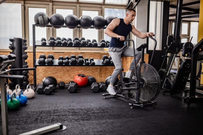 Man in a home gym garage on an air bike
