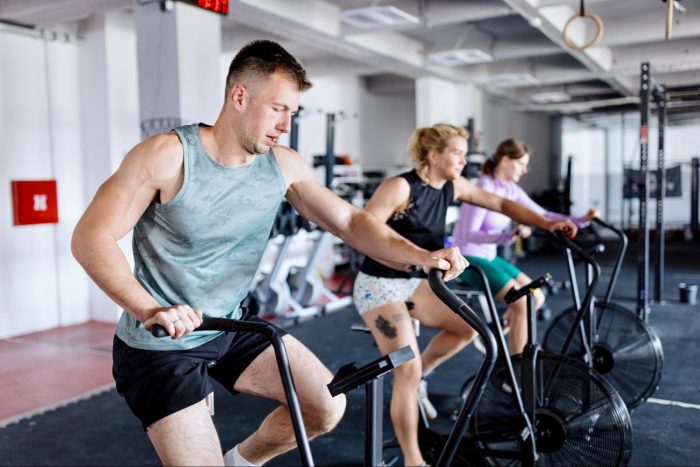 Man and two women in a workout class on an air bike