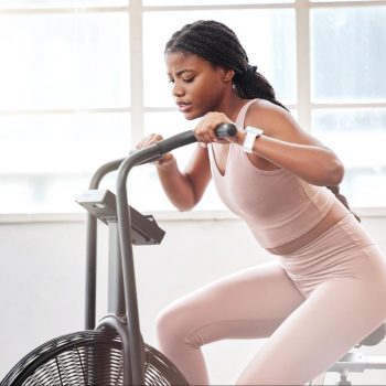 Woman in a pink gym set on an air bike