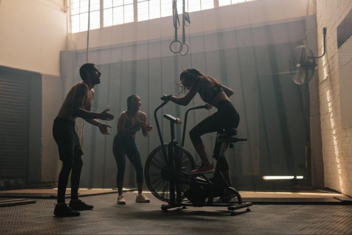 Two people encouraging someone on an air bike