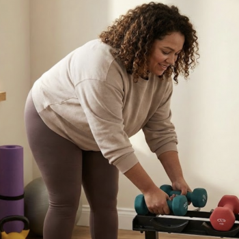 Woman picking up dumbbells at home gym