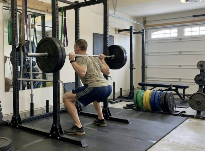 Man using a squat rack in garage