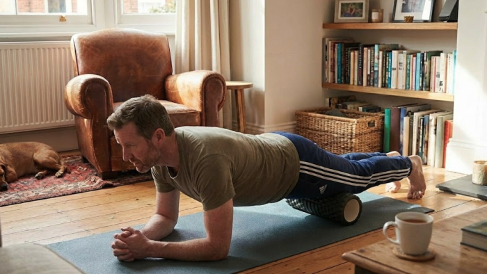 Man foam rolling his thighs at home