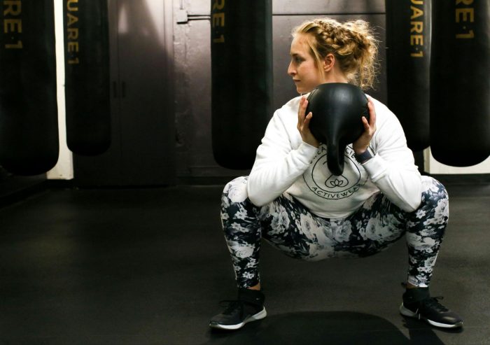 Woman doing a goblet squat with a kettlebell in a gym