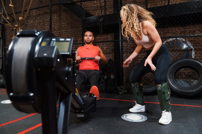 Woman coaching a man on a rowing machine